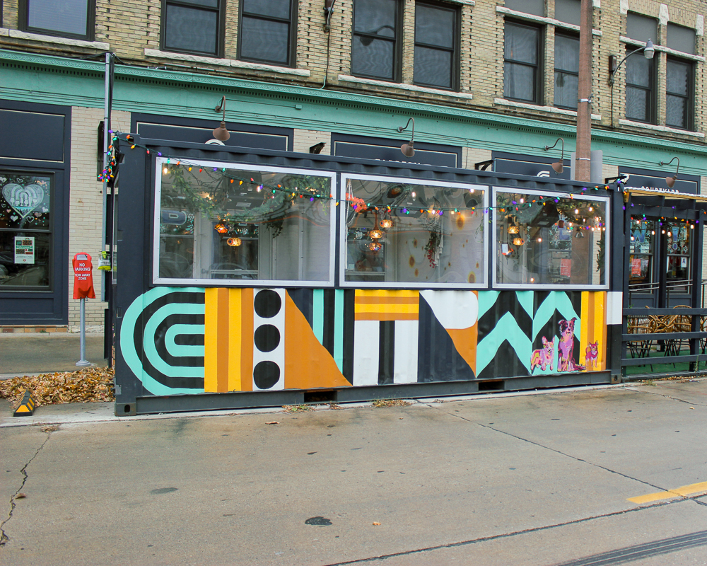 A painted and decorated shipping container repurposed for streetside dining